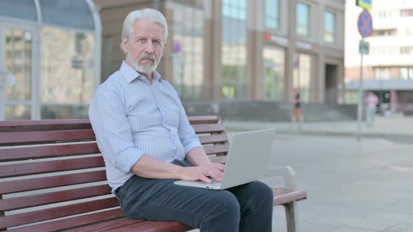 Rejecting Old Man in Denial While Using Laptop Sitting Outdoor on Bench