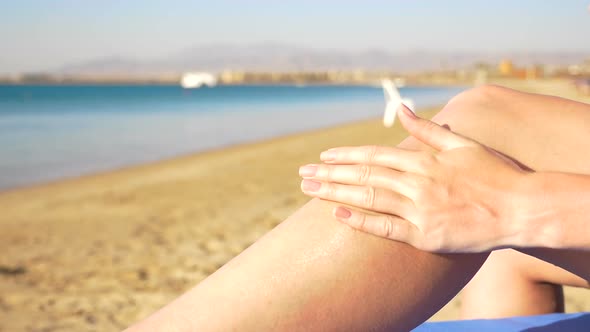 Girl with Beautiful Legs Rubbed Into the Skin Sunscreen on a Sea Background