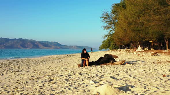 Modern fun woman relaxing spending quality time at the beach on clean white sand and blue background