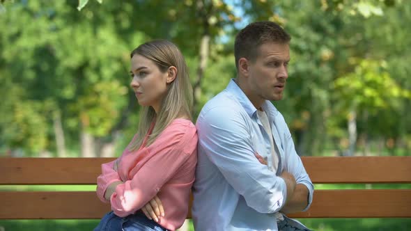 Offended Couple Sitting Back on Bench at Park, Looking at Each Other, Conflict