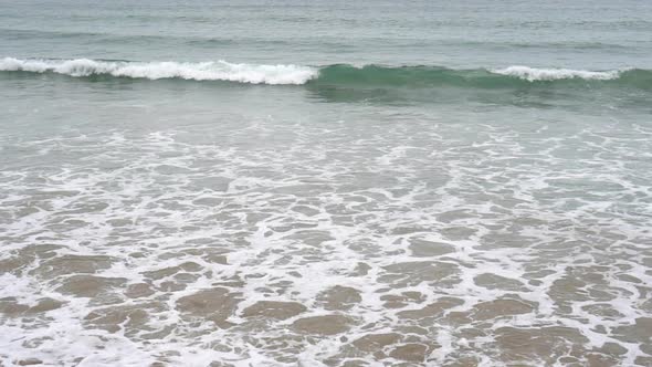 Calm evening ocean surf. Foamy waves fill the sandy beach