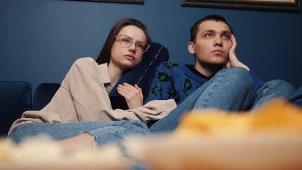 Young Good Looking Caucasian Man and Woman Watching an Interesting Film on TV Together with Popcorn