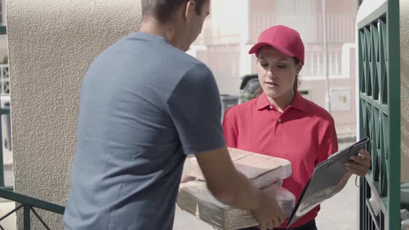 Female Courier Delivering Package To Customers Door
