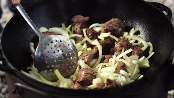 Mixing Onion with Meat for Uzbek Pilaf in a Cauldron