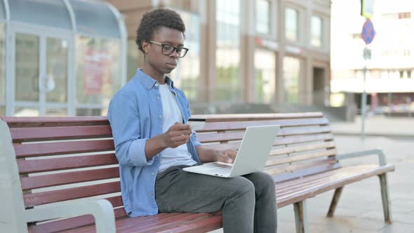 Young African Man Having Online Payment Problem with Laptop Outdoor