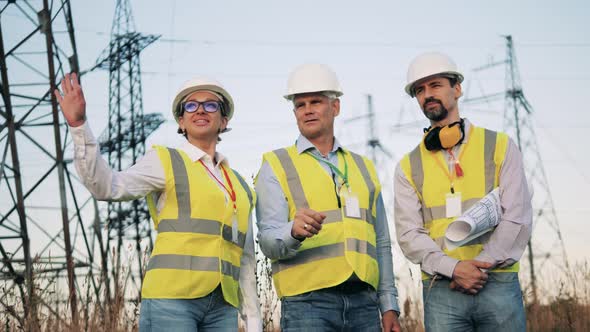 Electric Industry, Electrical Energy Production Concept. Electric Workers Stand in a Field While