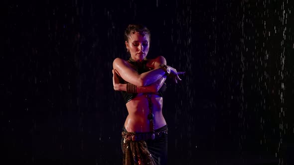 A Beautiful Woman is in a Studio in the Pouring Rain on a Black Background Dancing an Oriental Dance