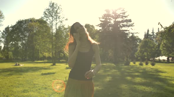 Smiling Young Attractive Female Walking at the Park Outdoors Talking By Phone