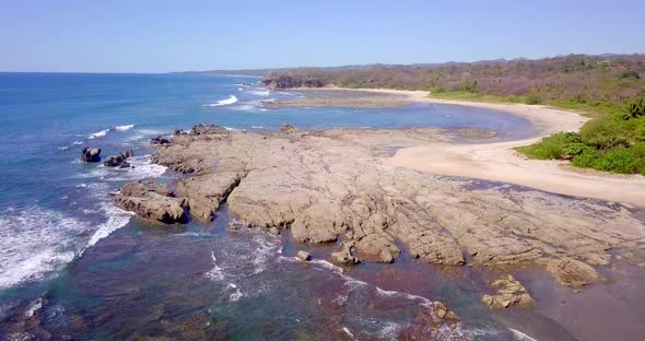 Aerial drone view of the beach, rocks and tide pools in Playa Palada, Guiones, Nosara, Costa Rica