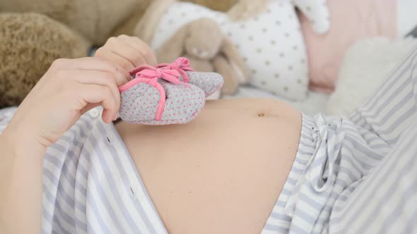 Pregnant Woman Lying With Little Shoes On Her Belly