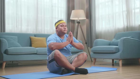 Fat Asian Man Doing Yoga In Sukhasana Pose At Home