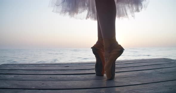 Legs of Ballerina in Pointies and Tutu Dancing on Tiptoes in Sunrays on Wooden Pier