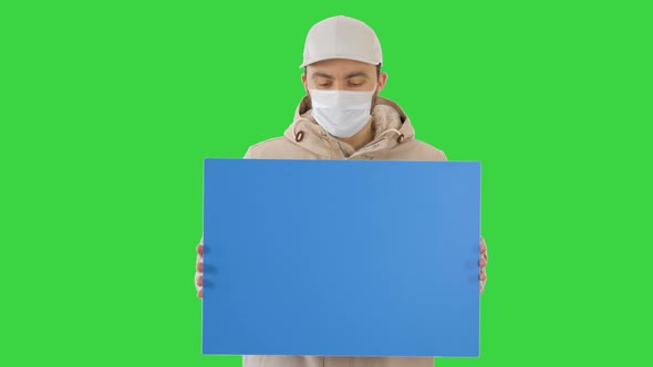 Casual Man with Copy Space Billboard Wearing Protective Mask on a Green Screen, Chroma Key.