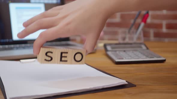 Wooden Cubes with Inscription Seo Hands are Laid Out on Office Table on Which There are Laptop