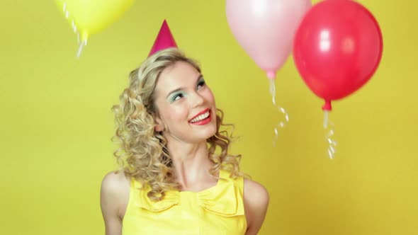 Young woman in party hat and floating balloons