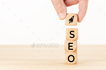 and holding a wooden block with rocket icon and SEO word. White background Copy space