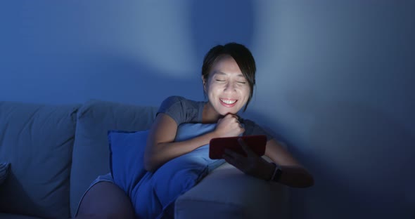 Woman watch on cellphone at night inside home