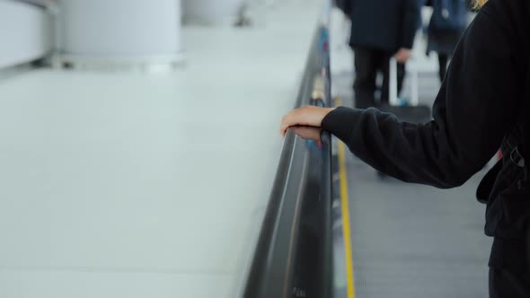 Woman in Airport Hold Rail on Moving Walkway