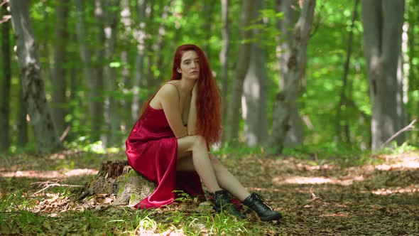 Redhead woman sitting on a tree stump