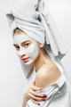 Beautiful young woman dressed in white clothes with a white towel on her hair and cosmetic mask on - PhotoDune Item for Sale