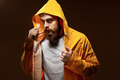 Red-haired guy with a beard and mustache dressed in a gray t-shirt and yellow jacket with a hood is - PhotoDune Item for Sale