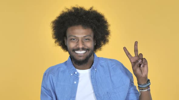 Victory Sign By AfroAmerican Man on Yellow Background