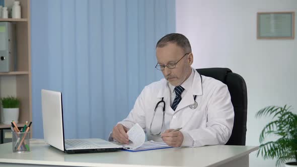 Head of Therapeutic Department Finishing His Workday, Filling in Medical Forms