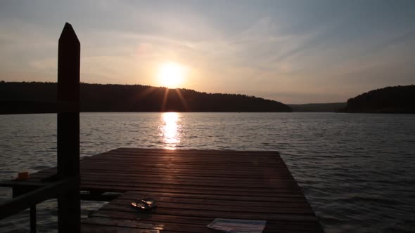 A Boy Jumps From a Pier Into the Sea or Lake in the Mountains on Warm Sunny Summer Day. Slow Motion