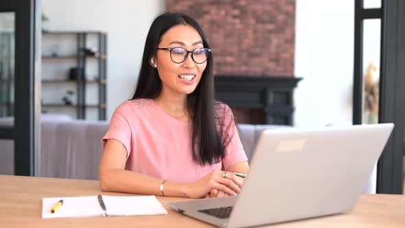 An Attractive Young Asian Woman is Using a Laptop for Video Call