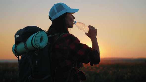 Woman Traveler with Backpack Drinking Water From a Bottle. Healthy Hiker Girl Drinking Water in