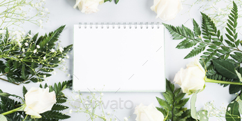 Open white notebook with white page in floral frame