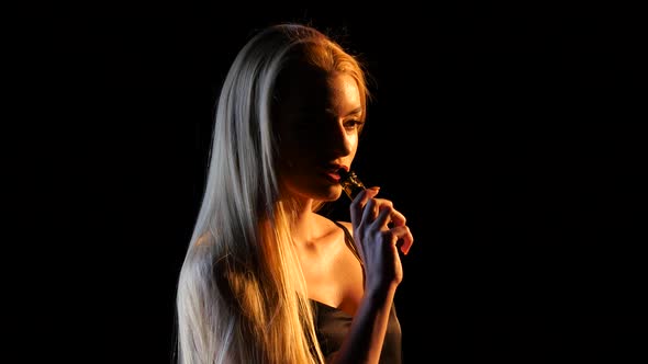 Girl Smokes an Electronic Cigarette in an Empty Room. Black Background. Silhouette