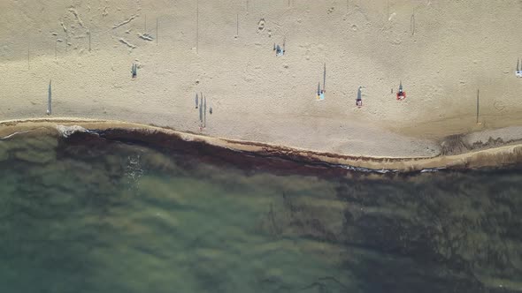 Top Down Drone Shot moving from Sea to Beach during a Hot Vacation Summer Season