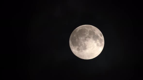 Clouds passing by the full moon, real time shot. Full moon at night with clouds in real time.