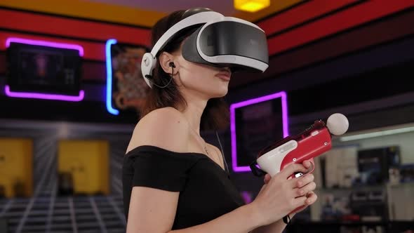 A Young Woman Wearing Virtual Reality Glasses and Hand Motion Controllers