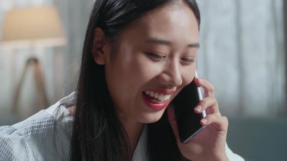 Close Up Of Asian Female Footwear Designer Talking On Smartphone While Working On A Laptop At Home