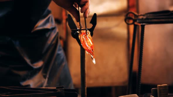 Close-up of glassblower shaping a molten glass