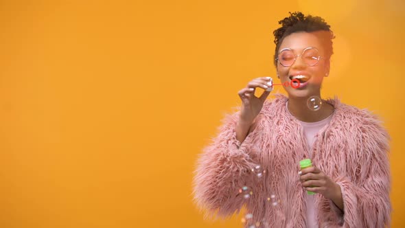 Pretty Girl Having Fun Making Soap Bubbles Childhood, Isolated Yellow Background