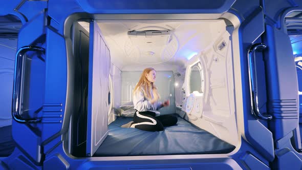 A Girl is Looking Into a Mirror of a Capsule Hotel Room