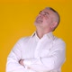 Caucasian male with folded arms looking up on yellow studio background. - VideoHive Item for Sale