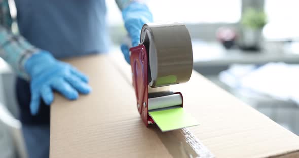 Postal Worker Packing Cardboard Boxes with Tape Closeup