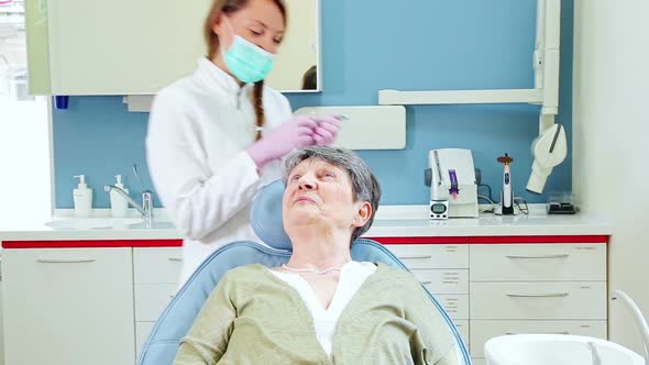 Elderly woman doing high five with dentist after receiving injection