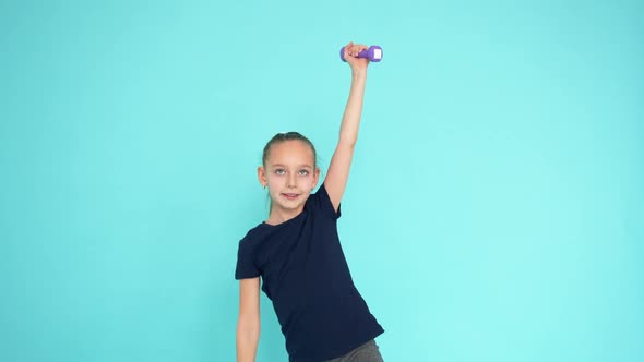 Cheerful Girl Teenager Lifting Dumbbells at Aerobics Gym on Turquoise Background