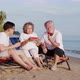 Couple of senior elderly retirement and a son enjoy and eating watermelon on the beach together - VideoHive Item for Sale