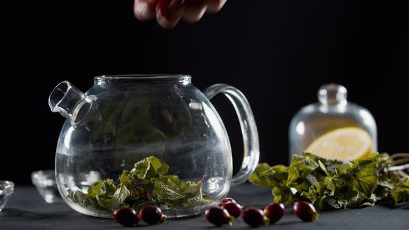 Dropping Mint Leaves, Rosehip and Lemons Into a Teapot, 