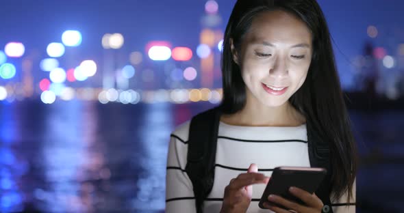 Young Woman Looking at Mobile Phone in City at Night