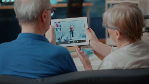 Senior Couple Attending Online Meeting with Doctor on Digital Tablet