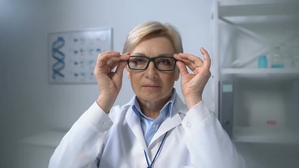 Experienced Mature Female Therapist Adjusting Eyeglasses, Looking Into Camera