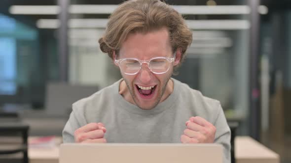 Portrait of Successful Businessman Celebrating on Laptop at Work