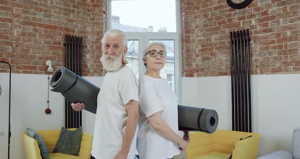 Old Couple in Sportswear Posing on Camera with Yoga Mats while Starting to do Exercises at Home